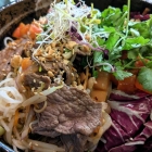 Foto zu Restaurant Maison Tom: Bun Bo Nam Bo - im Wok gebratenes Roastbeef auf warmen Reisnudeln mit Wildkräutersalat